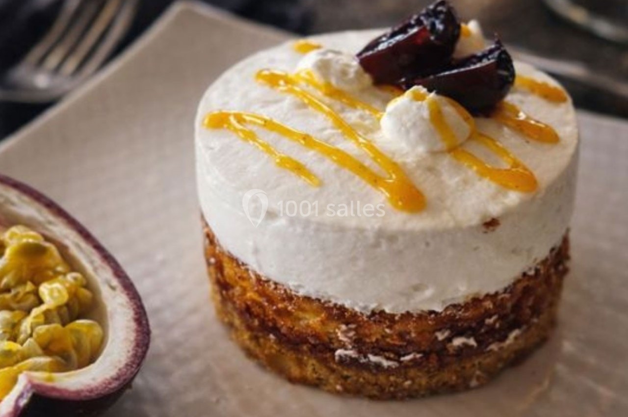Gâteau individuel avec base biscuitée, mousse blanche, coulis jaune et garniture de fruits rouges et fruit de la passion.