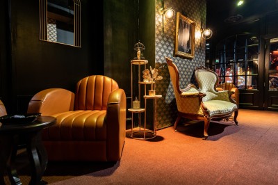 Canapé en cuir beige dans une pièce tamisée, avec un avis de recherche encadré accroché au mur.