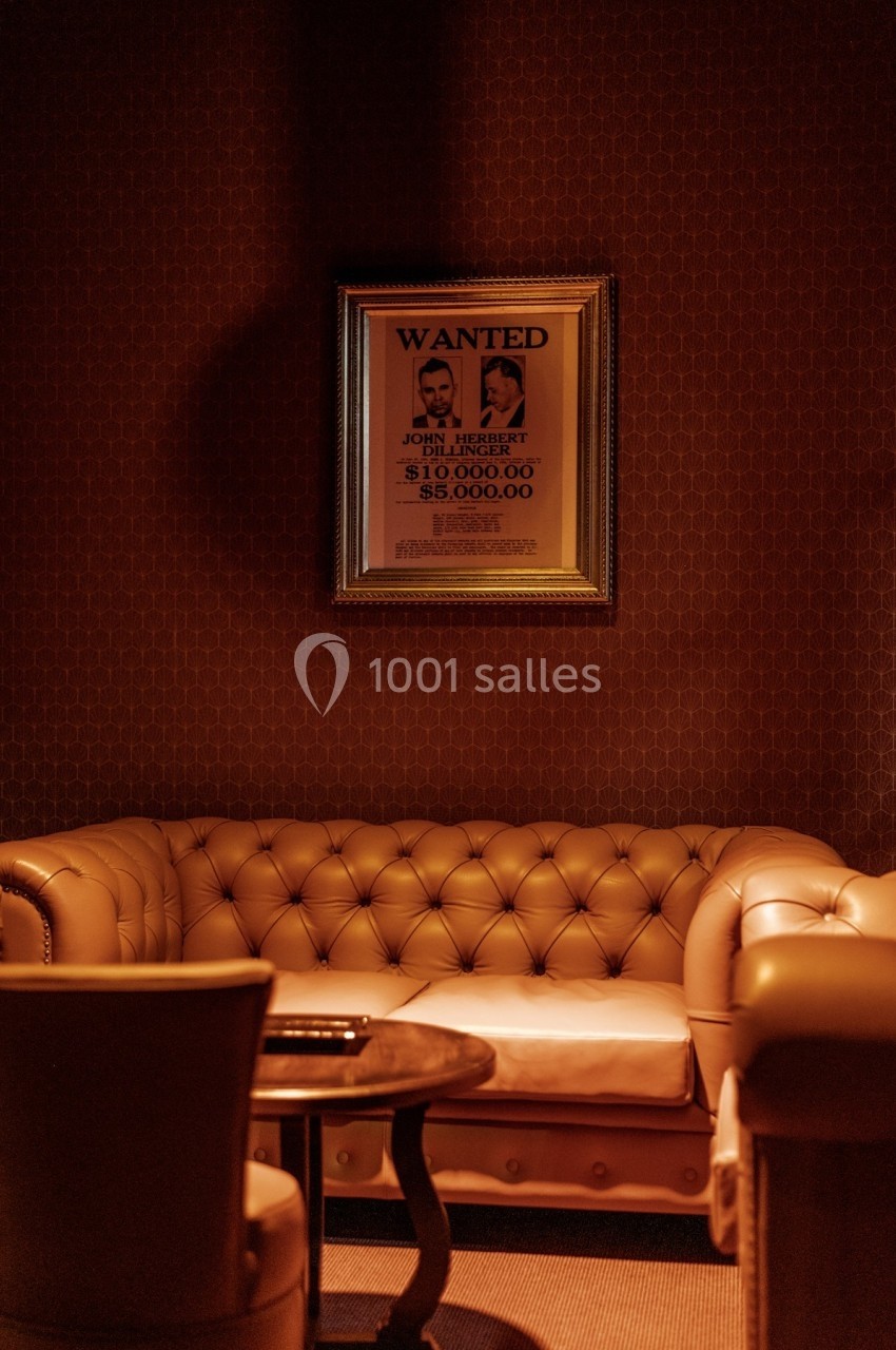 Canapé en cuir beige dans une pièce tamisée, avec un avis de recherche encadré accroché au mur.