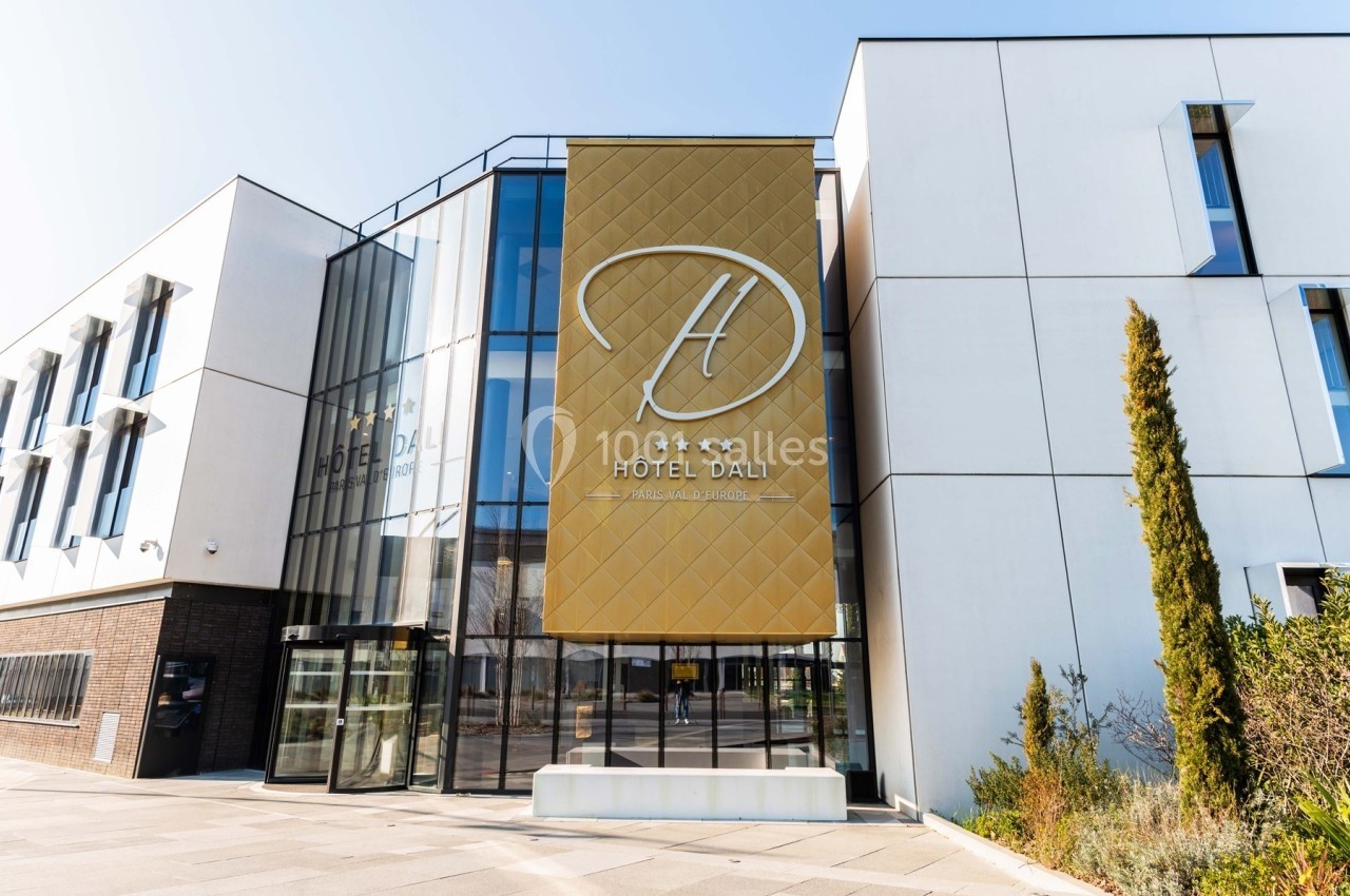 Façade moderne de l'Hôtel Dali avec une grande enseigne dorée et des baies vitrées.
