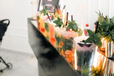 Salle de réception lumineuse avec tables rondes dressées, chaises blanches et buffets alignés sur le côté.