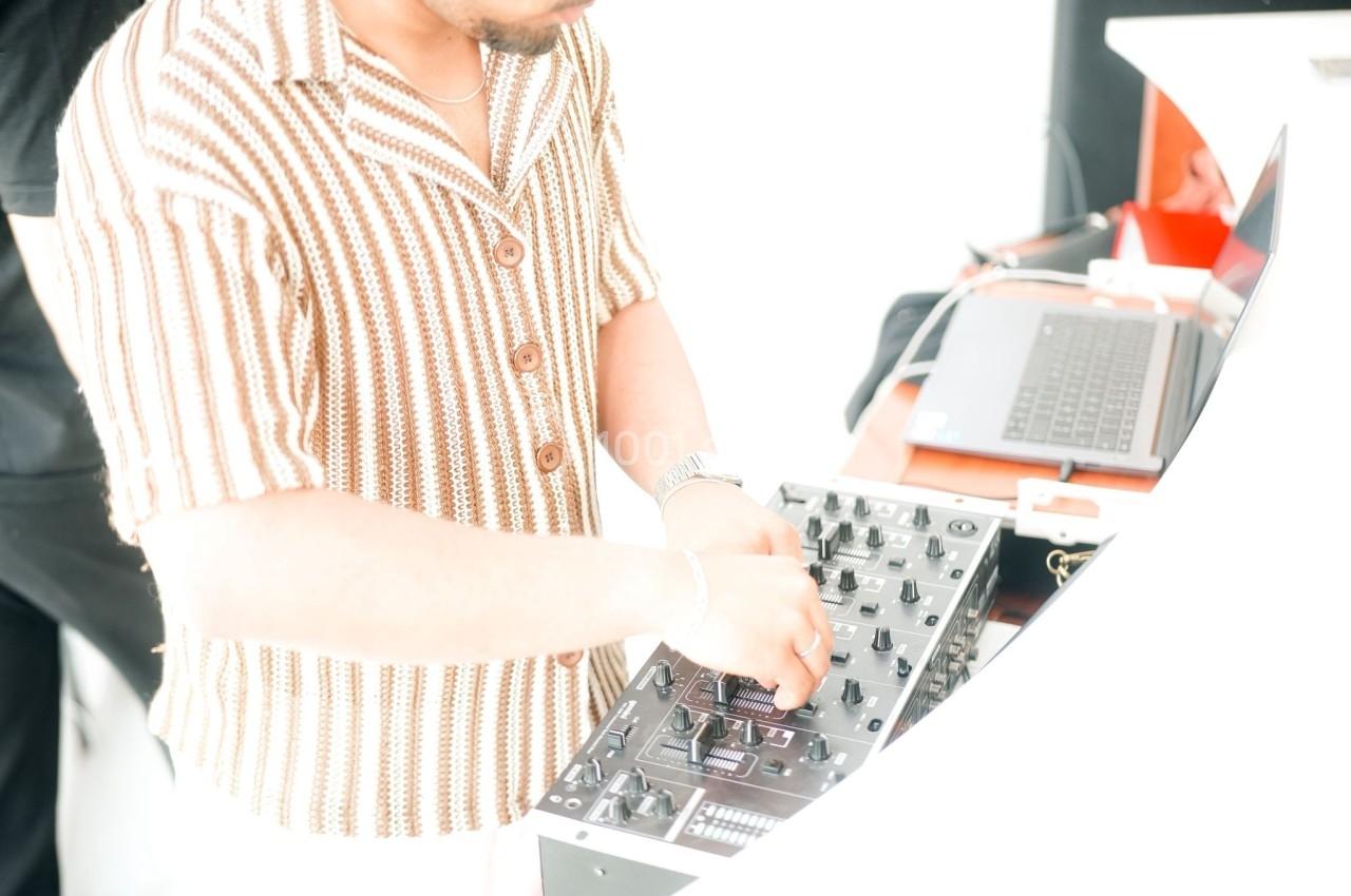 Un homme ajuste les réglages d'une table de mixage, avec un ordinateur portable à proximité.