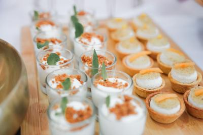 Salle de réception lumineuse avec tables rondes dressées, chaises blanches et buffets alignés sur le côté.
