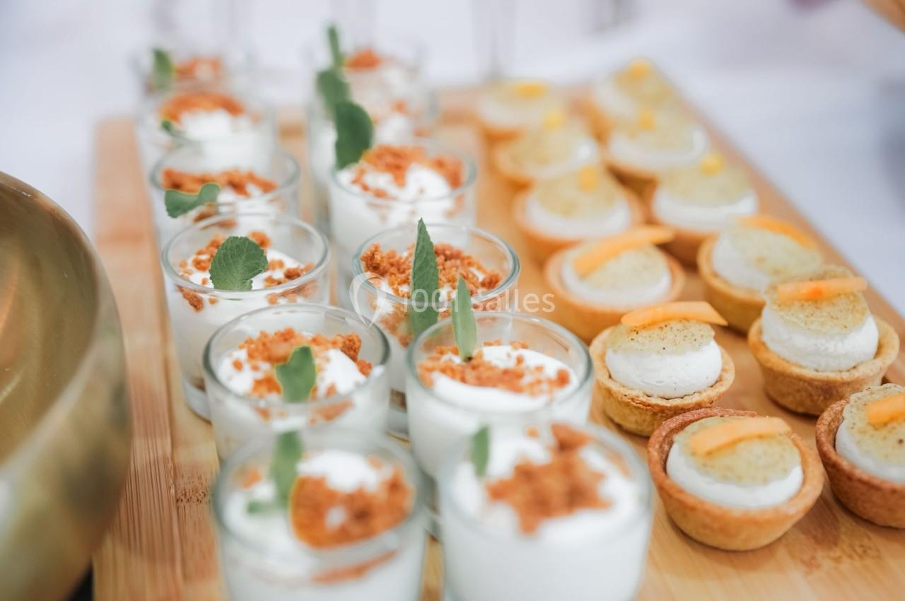 Desserts variés présentés sur un plateau en bois, incluant verrines garnies et tartelettes décorées.