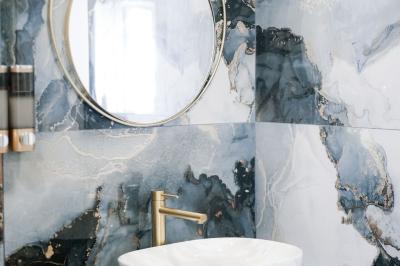 Salle de réception lumineuse avec tables rondes dressées, chaises blanches et buffets alignés sur le côté.