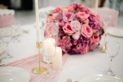 Salle de réception lumineuse avec tables rondes dressées, chaises blanches et buffets alignés sur le côté.