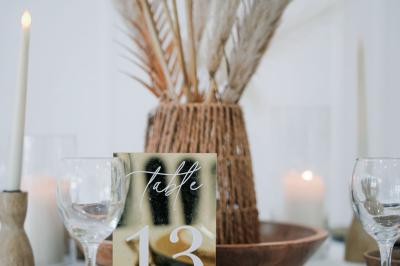 Salle de réception lumineuse avec tables rondes dressées, chaises blanches et buffets alignés sur le côté.