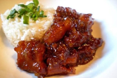 Tranches d'ananas caramélisées disposées sur un plat blanc, décorées de feuilles de menthe fraîche.