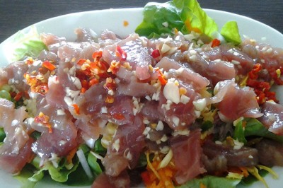 Tranches d'ananas caramélisées disposées sur un plat blanc, décorées de feuilles de menthe fraîche.