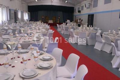 Espace extérieur décoré de tapis, lanternes et coussins, avec une table dressée en arrière-plan.