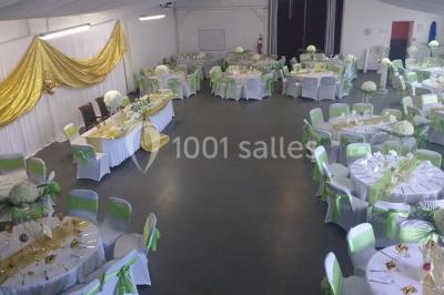 Espace extérieur décoré de tapis, lanternes et coussins, avec une table dressée en arrière-plan.