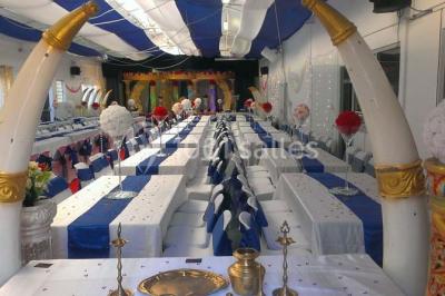 Espace extérieur décoré de tapis, lanternes et coussins, avec une table dressée en arrière-plan.