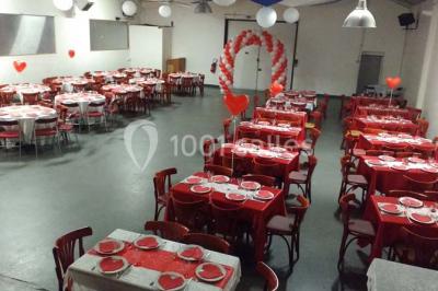 Espace extérieur décoré de tapis, lanternes et coussins, avec une table dressée en arrière-plan.