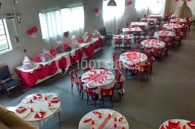 Espace extérieur décoré de tapis, lanternes et coussins, avec une table dressée en arrière-plan.