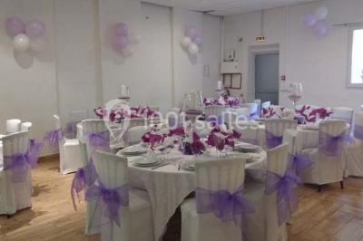 Espace extérieur décoré de tapis, lanternes et coussins, avec une table dressée en arrière-plan.