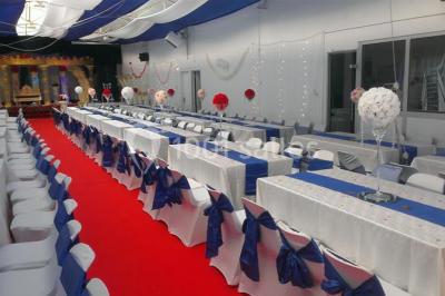 Espace extérieur décoré de tapis, lanternes et coussins, avec une table dressée en arrière-plan.