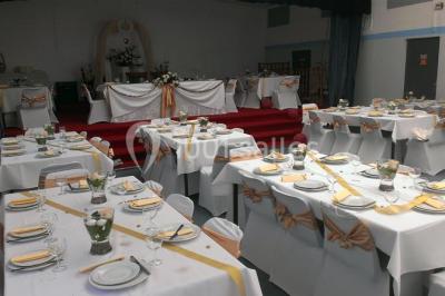 Espace extérieur décoré de tapis, lanternes et coussins, avec une table dressée en arrière-plan.