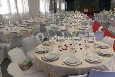 Espace extérieur décoré de tapis, lanternes et coussins, avec une table dressée en arrière-plan.