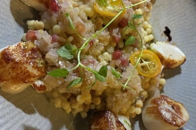 Dessert composé d'un gâteau au chocolat avec une garniture blanche et d'une boule de glace sur un lit de crumble.