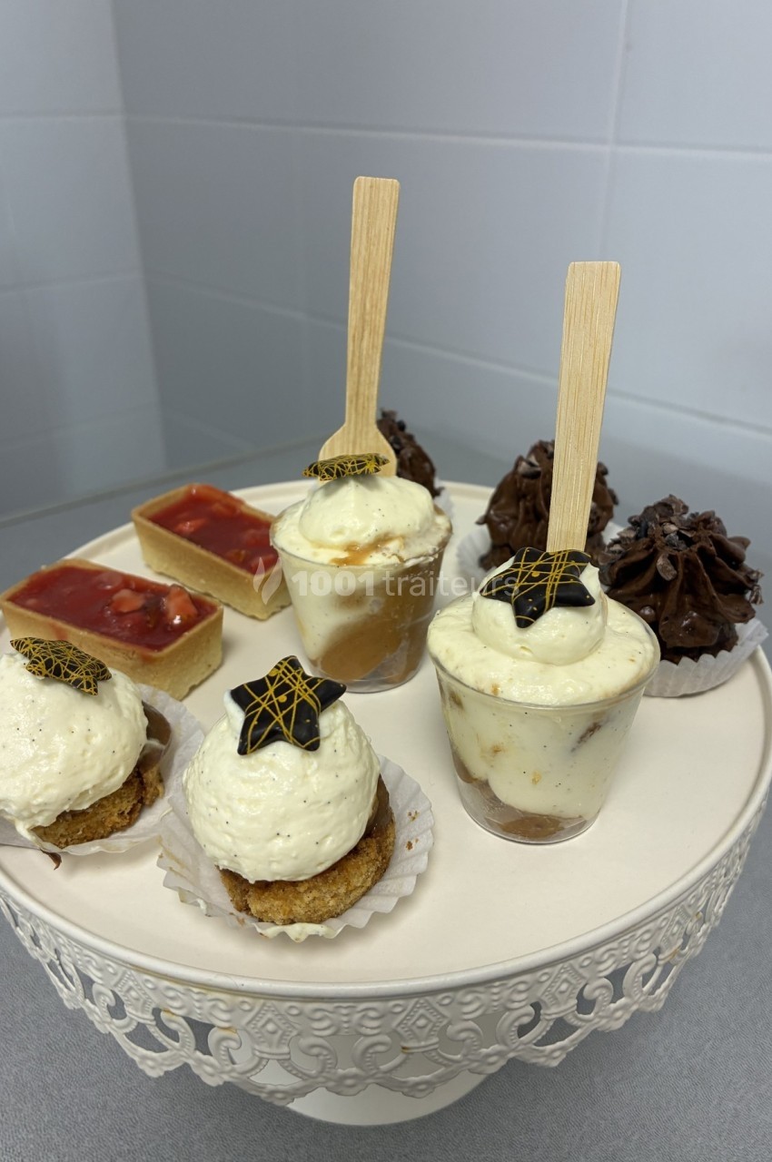 Assortiment de desserts variés présentés sur un présentoir blanc, incluant verrines, tartelettes et gâteaux.