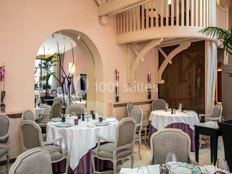 Salle de restaurant élégante avec tables dressées, chaises capitonnées et décoration lumineuse dans un cadre raffiné.
