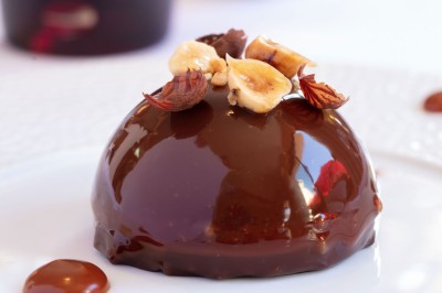 Sculpture moderne d'un taureau noir aux cornes longues et rouges, avec une posture dynamique et stylisée.