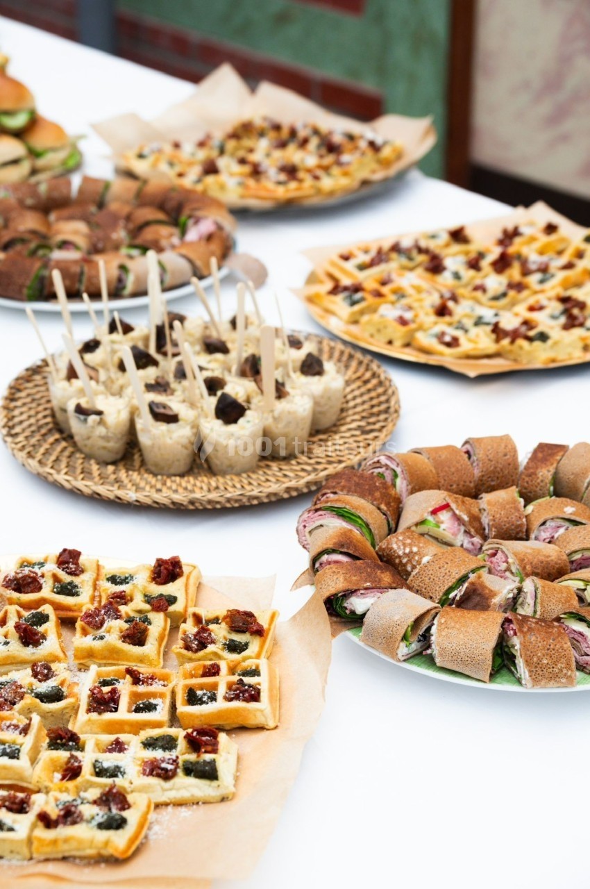 Assortiment de plats salés comprenant gaufres, roulés, verrines et autres amuse-bouches sur une table blanche.
