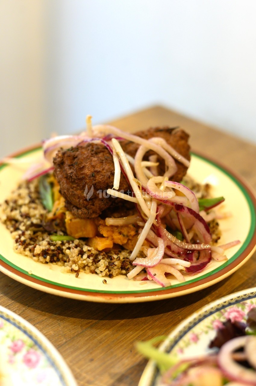 Assiette de quinoa garnie de légumes, boulettes frites et oignons rouges marinés.