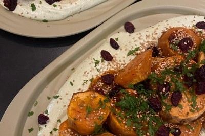 Assiette de magret de canard tranché sur purée de patates douces, garnie de persil et accompagnée d'une sauce.