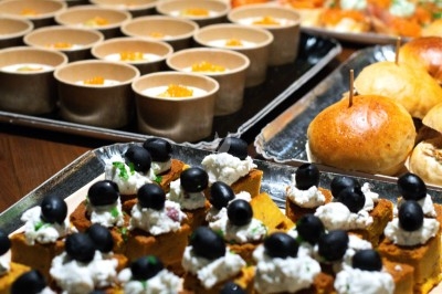 Plateaux de bouchées apéritives variées, incluant des verrines, des pains et des amuse-bouches garnis d'olives noires.