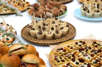 Buffet varié avec mini-burgers, gaufres garnies et amuse-bouches sur une table blanche.
