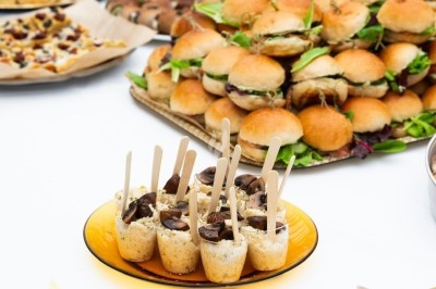 Buffet avec mini-sandwichs, roulés, verrines et autres amuse-bouches disposés sur une table blanche.