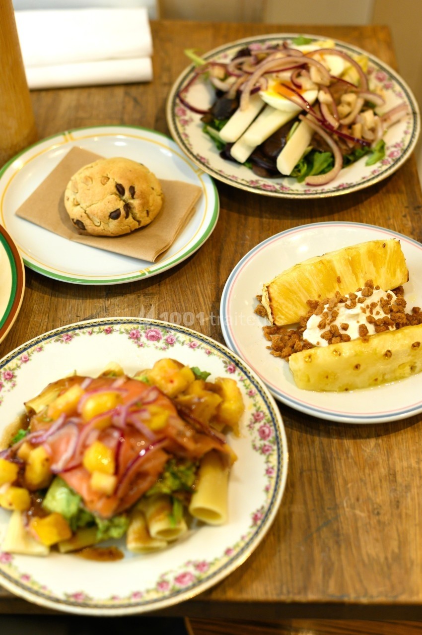 Assiette de pâtes aux légumes, salade, cookie aux pépites de chocolat et dessert à l'ananas sur une table en bois.
