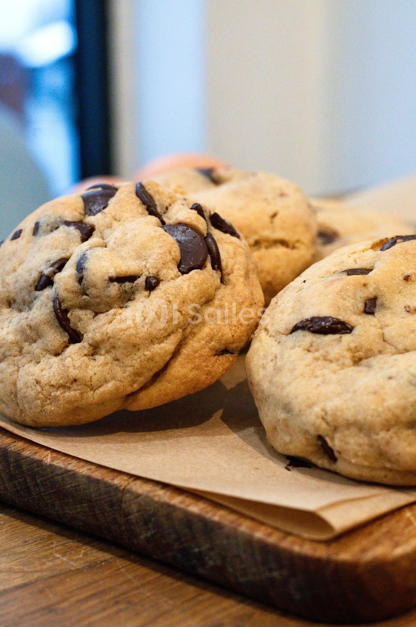 Cookies aux pépites de chocolat posés sur une planche en bois, avec un fond flou.