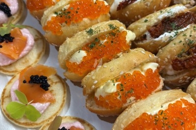 Assortiment de bouchées apéritives avec blinis au saumon et mini-sandwichs garnis d'œufs de poisson et de crème.