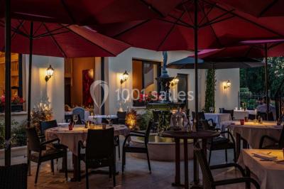 Dessert au glaçage chocolat brillant, garni de noisettes entières et concassées, présenté sur une assiette blanche.