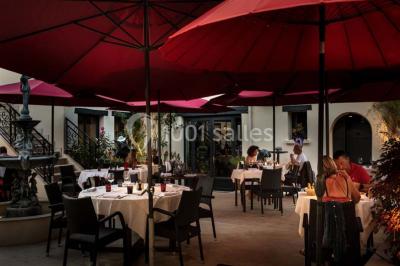 Dessert au glaçage chocolat brillant, garni de noisettes entières et concassées, présenté sur une assiette blanche.