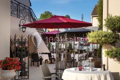 Dessert au glaçage chocolat brillant, garni de noisettes entières et concassées, présenté sur une assiette blanche.