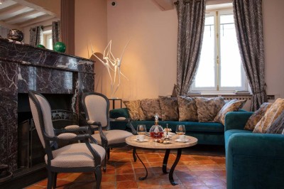 Dessert au glaçage chocolat brillant, garni de noisettes entières et concassées, présenté sur une assiette blanche.