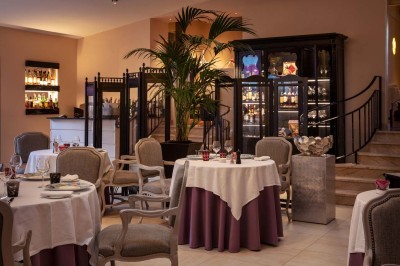 Dessert au glaçage chocolat brillant, garni de noisettes entières et concassées, présenté sur une assiette blanche.