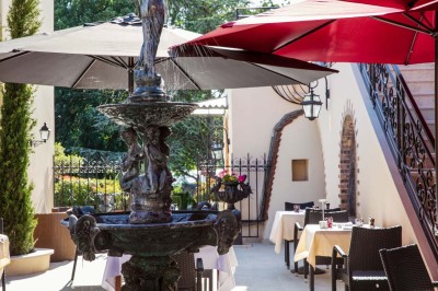 Dessert au glaçage chocolat brillant, garni de noisettes entières et concassées, présenté sur une assiette blanche.