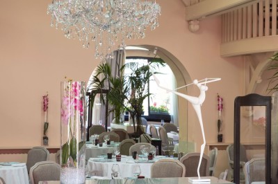 Dessert au glaçage chocolat brillant, garni de noisettes entières et concassées, présenté sur une assiette blanche.