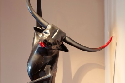 Dessert au glaçage chocolat brillant, garni de noisettes entières et concassées, présenté sur une assiette blanche.