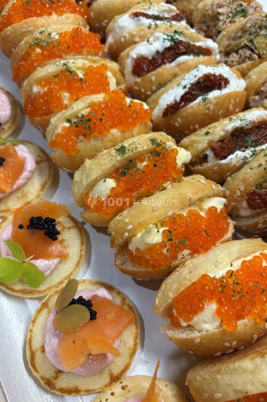 Assortiment de bouchées apéritives avec blinis au saumon et caviar, et mini-sandwichs garnis de crème et œufs de poisson.