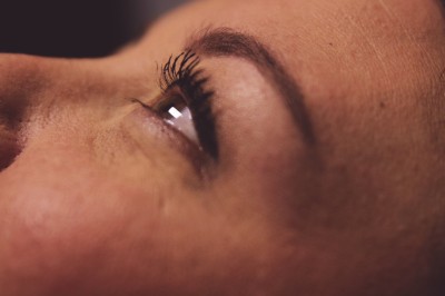 Femme assise dans une lumière tamisée, entourée de verres, regardant vers l'objectif.