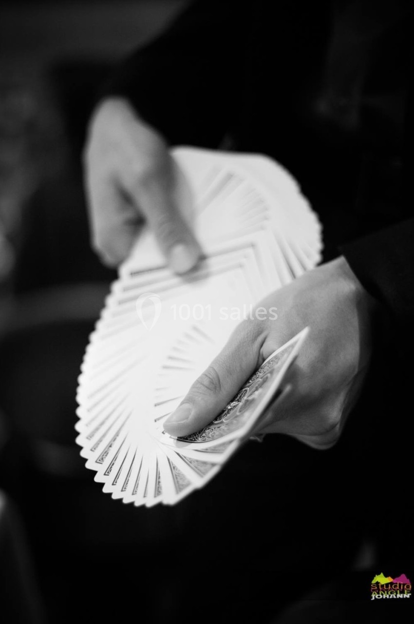 Main tenant un éventail de cartes à jouer dans un contexte en noir et blanc.