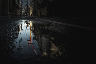 Femme assise dans une lumière tamisée, entourée de verres, regardant vers l'objectif.