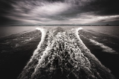 Femme assise dans une lumière tamisée, entourée de verres, regardant vers l'objectif.