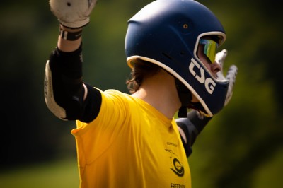 Femme assise dans une lumière tamisée, entourée de verres, regardant vers l'objectif.