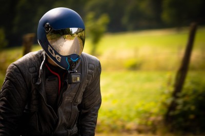 Femme assise dans une lumière tamisée, entourée de verres, regardant vers l'objectif.